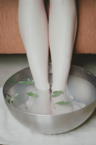 A relaxing foot bath with fresh green leaves in a silver basin, providing a soothing spa experience