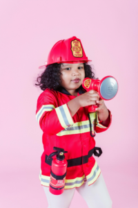 Little ethnic girl in fireman costume using loudspeaker