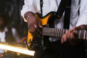 Person in White Long Sleeve Shirt Playing Black and Yellow Guitar