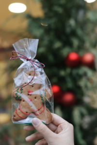 Hand Holding Decorated Gingerbread Man in Wrapped in Plastic
