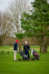 Two men are in the golf course with their golf bags