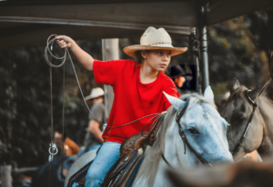 A Kid in Red Shirt Riding a White Horse
