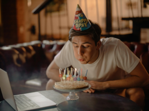 Man in White Crew Neck T-shirt Sitting by the Table With Cake