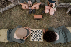 Kids Playing Chess while Lying Down on Brown Grass
