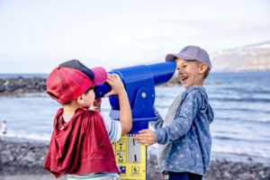 Boys Wearing Cap Looking Each Other in the Telescope