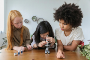 Focused little girls with microscope in room
