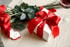 Gift Box with Red Ribbon beside Red Roses