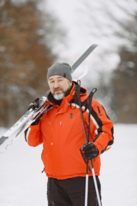 Man in Orange Jacket Holding Snow Ski Blades