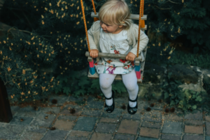 Girl in White Jacket Riding on Swing