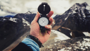 Man Hand Holding Compass in Mountains