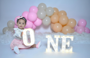 Girl Sitting with One Year Birthday Decorations
