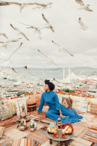 A Woman Sitting on the Roof Top With Decorative Cushions