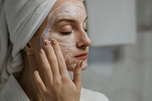 A woman is applying face mask on her face for regular skincare