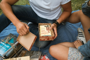 Man in White T-Shirt Holding Box with Book Inside