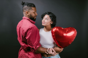 Couple Looking at Each Other While Holding a Red Heart Shaped Balloon