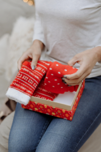 A Woman Holding Christmas Socks from a Red Gift Box