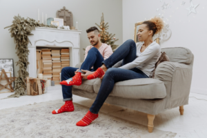 Man and Woman Sitting on Brown Couch Wearing Red and White Socks