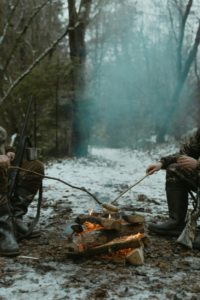 Two men are cooking food while they are going for hunting