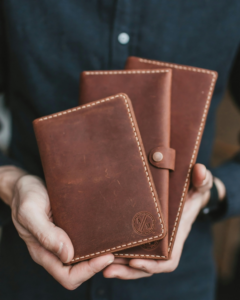 A man is holding three classic leather wallets in his hand