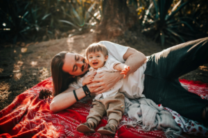 A Man Playing with his Son on a Picnic Blanket