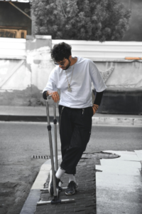 Man in White Shirt and Black Pants Standing near the Metal Stand