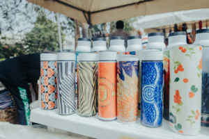 Water Bottle Decorated with Stickers on the Rocky Seashore