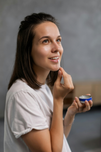 A woman is applying lip balm on her lip