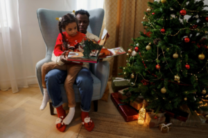 Dad and Daughter Reading a Fairy Tale Book While Sitting Beside a Christmas Tree
