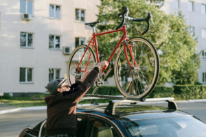 a man is keeping his bicycle on the Roof racks of a car