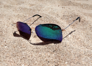 a black color sunglass on the sand beach