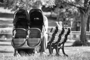 Man with Twins Stroller Sitting on Bench in Park
