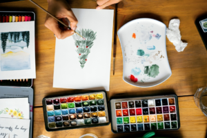 A Person Painting a Christmas Tree on Paper
 With Watercolor