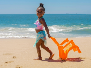 A Young Girl in Swimsuit Pulling a Chair on the Beach
