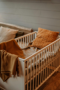 A Throw Pillow and Blanket on a White Crib