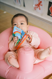 Adorable Baby Relaxing in Inflatable Seat Reading Book
